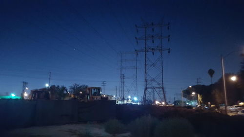 Illuminated modern buildings against clear blue sky at night