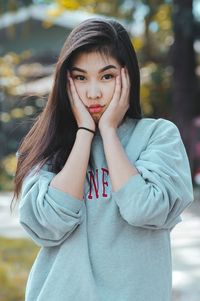 Portrait of beautiful young woman standing against trees