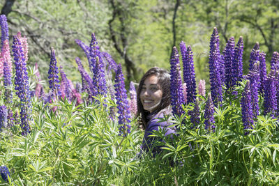 Portrait of woman with purple flowers on field