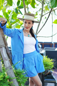 Portrait of smiling young woman standing against plants