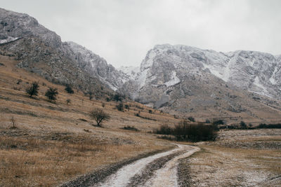 Road by mountains against sky