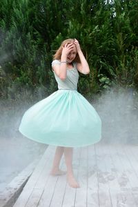 Portrait of girl wearing blue dress amidst fog against plants