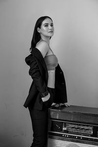 Portrait of woman standing by vintage record player against wall