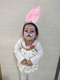 Portrait of cute girl standing against wall