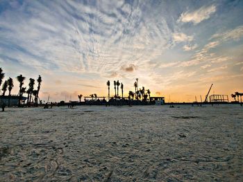 Pier at beach against sky during sunset