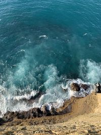 High angle view of sea waves splashing on rock formation