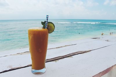 Drink on table by sea against sky