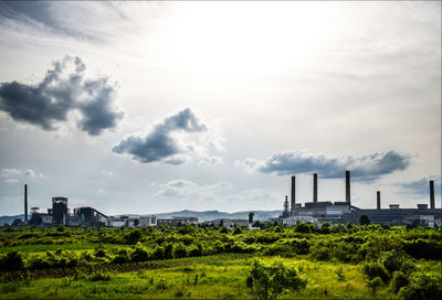 Smoke emitting from factory against sky