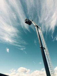 Low angle view of crane by building against sky