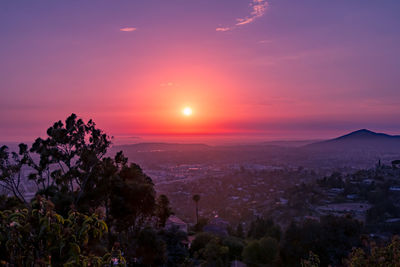 Scenic view of landscape against dramatic sky during sunset
