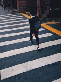 Full length rear view of man walking on crosswalk