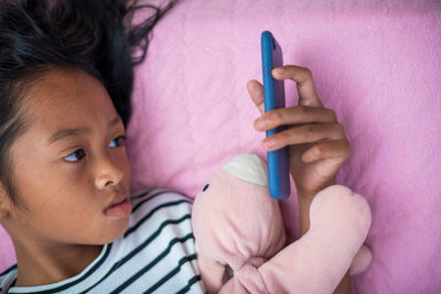 Portrait of woman holding mobile phone while relaxing on bed at home