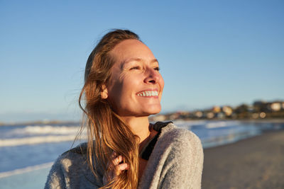 Tranquil female enjoying sunset in summer on beach near sea looking away