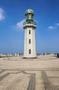 Lighthouse amidst buildings against sky