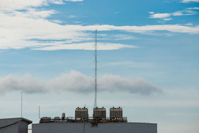 Low angle view of communications tower and buildings against sky