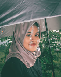Portrait of smiling teenage girl holding umbrella standing outdoors