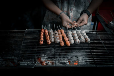 Midsection of person preparing food on barbecue grill