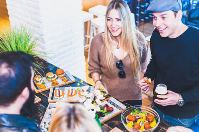 High angle view of happy friends having food at table in bar