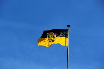 Low angle view of yellow flag against blue sky