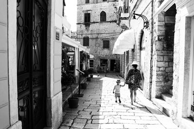 People walking on footpath amidst buildings in city