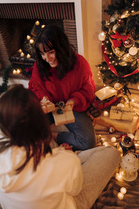 Midsection of woman sitting in christmas tree at home