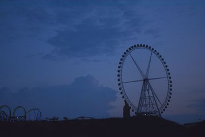 Low angle view of ferris wheel against cloudy sky