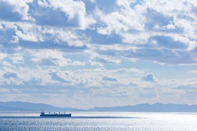 Boats in sea against cloudy sky