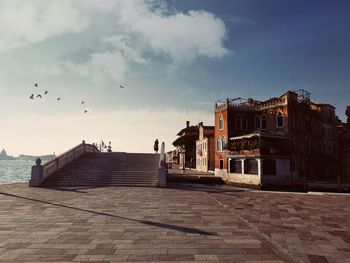 Birds flying over building against sky