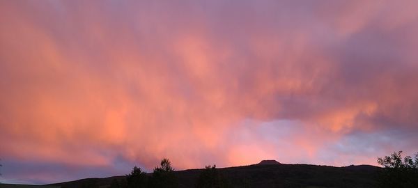 Silhouette landscape against dramatic sky during sunset