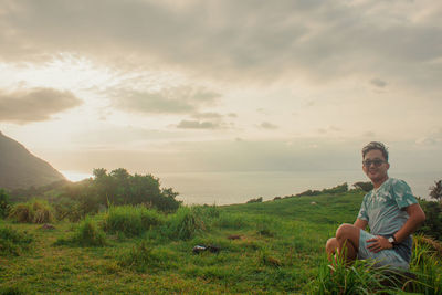 Full length of man sitting on shore against sky