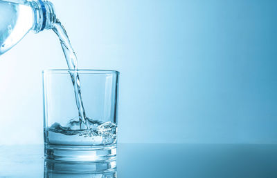 Close-up of glass of water against blue background