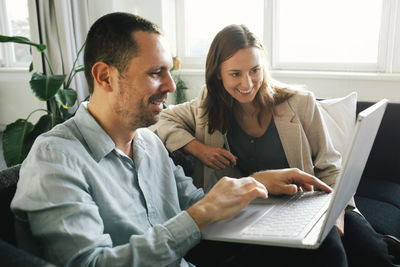 Happy business professionals working together on laptop while sitting at office