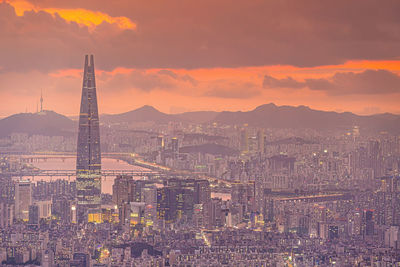 Illuminated cityscape against sky during sunset