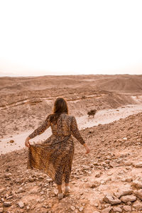 Woman wearing a long dress staring at the horizon in the desert