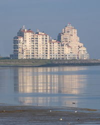 Buildings by lake against sky in city