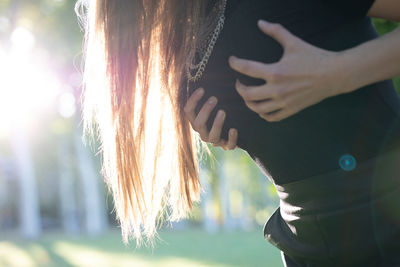 Midsection of woman pressing breast while standing outdoors