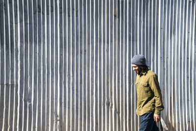 Smiling, young, african-american man walks in front of metal wall