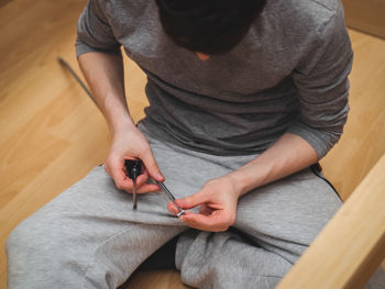 Young caucasian guy hand-twisting a screw with a screwdriver on a metal part of the bed