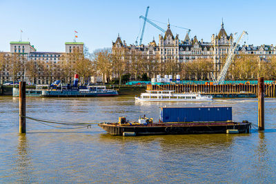 Sailboats in river against buildings in city