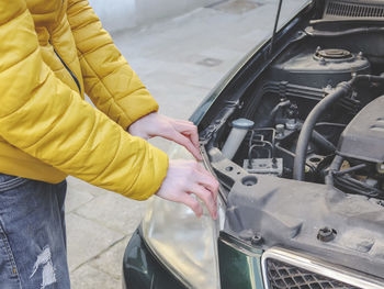 A young caucasian guy in a yellow jacket inspects the internal breakdown of the front headlight