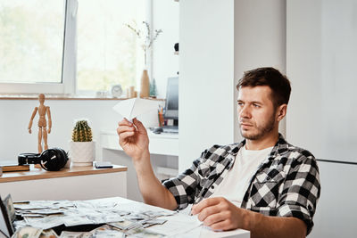 Man with laptop and dollar banknotes plays with paper plain