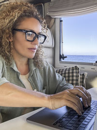 Portrait of young woman using laptop at beach