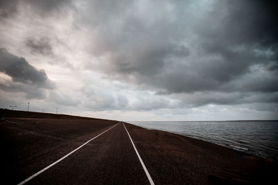 Empty road against cloudy sky