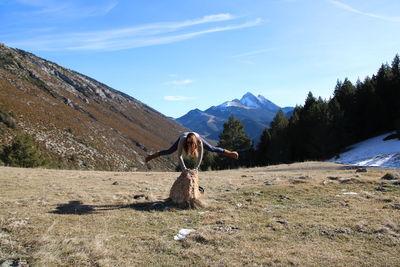 Woman doing handstand on rock against mountains