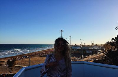 Woman standing by railing against beach