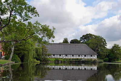 House by lake against sky