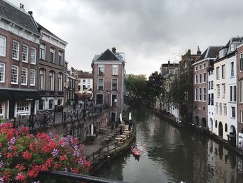 Canal amidst buildings in city against sky