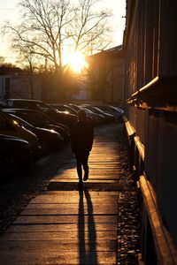 Full length of silhouette person on street against sky during sunset