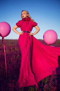 Fashionable beautiful young woman in a pink dress in a field with wildflowers