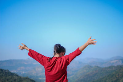 Rear view of man with arms outstretched against mountain